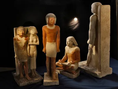 Ancient Egyptian statues and art depict scribes holding cross-legged or kneeling positions while working.