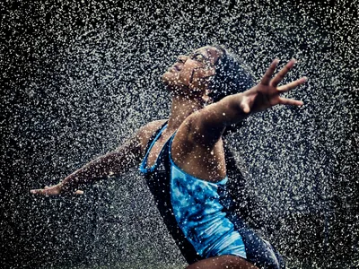 A girl runs through sprinkles of water to cool off on a hot summer day.

