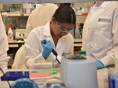 A young girl wears a lab coat, safety goggles and blue latex gloves in a research laboratory