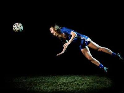 A high school soccer player remembers to keep her eye on the ball, even when soaring midair.

