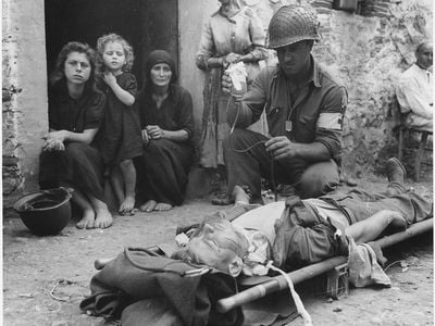 Private Roy W. Humphrey is being given blood plasma after he was wounded by shrapnel in Sicily in August 1943.