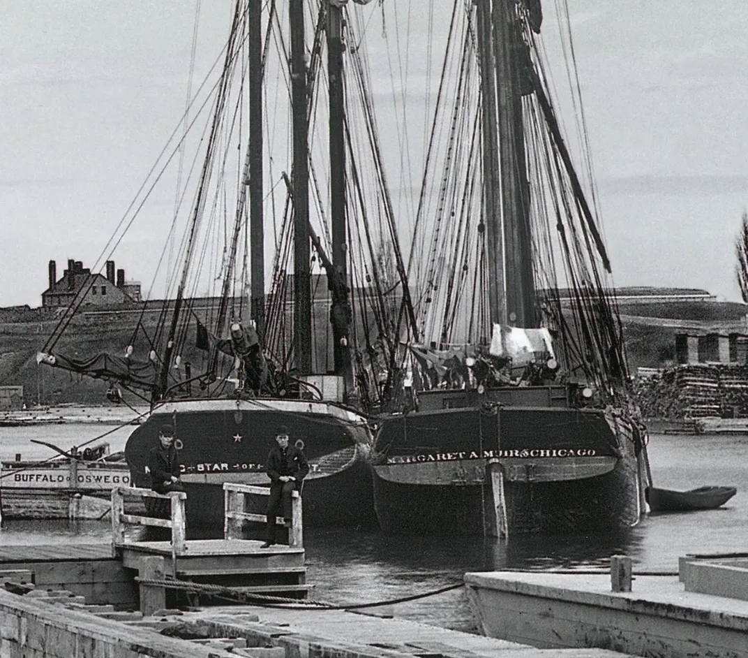 Black and white photo of two ships next to each other at a dock