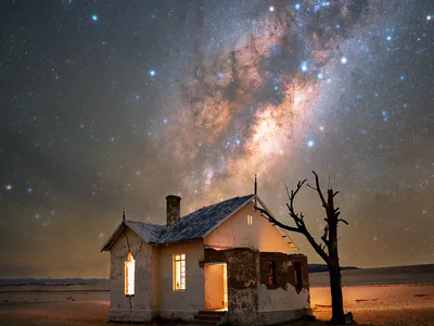 An abandoned house in the Namib Desert with the Milky Way rising above it.