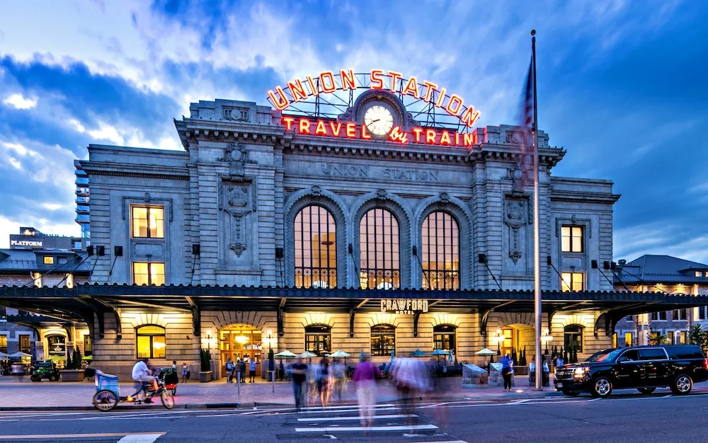 A large building at dusk with a sign that says Union Station Travel by Train