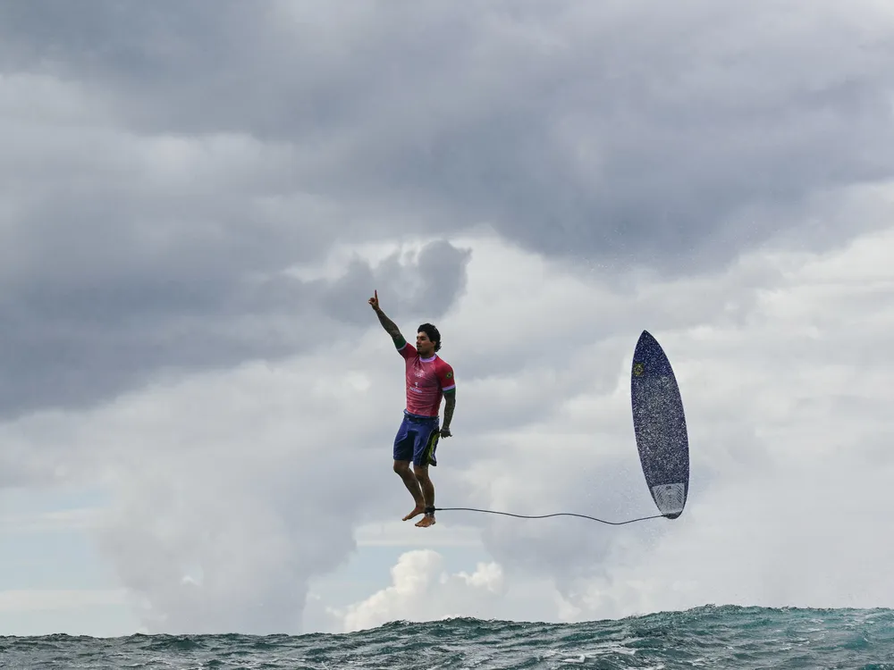 Surfer and his surfboard floating through the air above ocean water