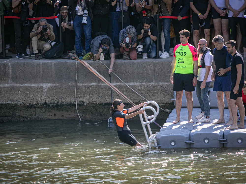 Woman climbing a ladder into water wearing a wetsuit