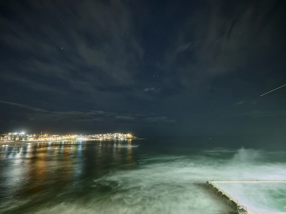 Meteor streaking across the sky with city lights in the background