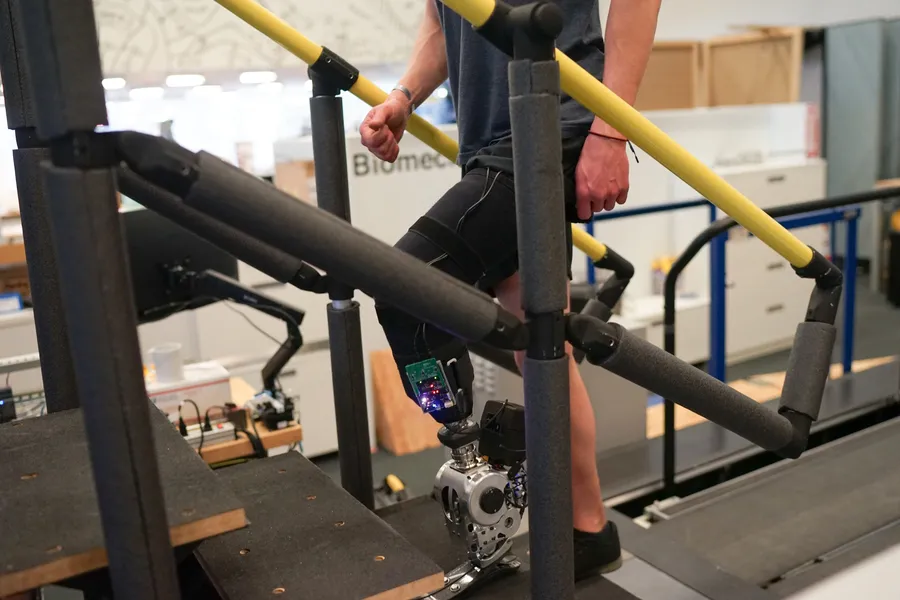 A person with a prosthetic lower leg walks up a flight of stairs