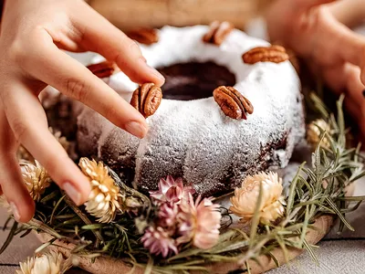 A hand places a pecan on a decadent dessert