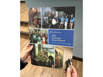 Hard-copy of the FY2023 Smithsonian Education Impact Report held in someone’s hands.