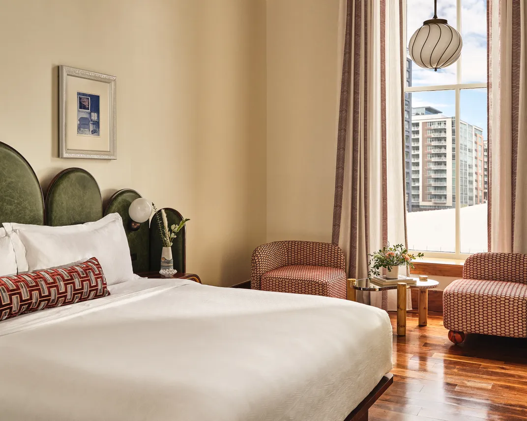 A bright airy hotel room with a bed and a big window